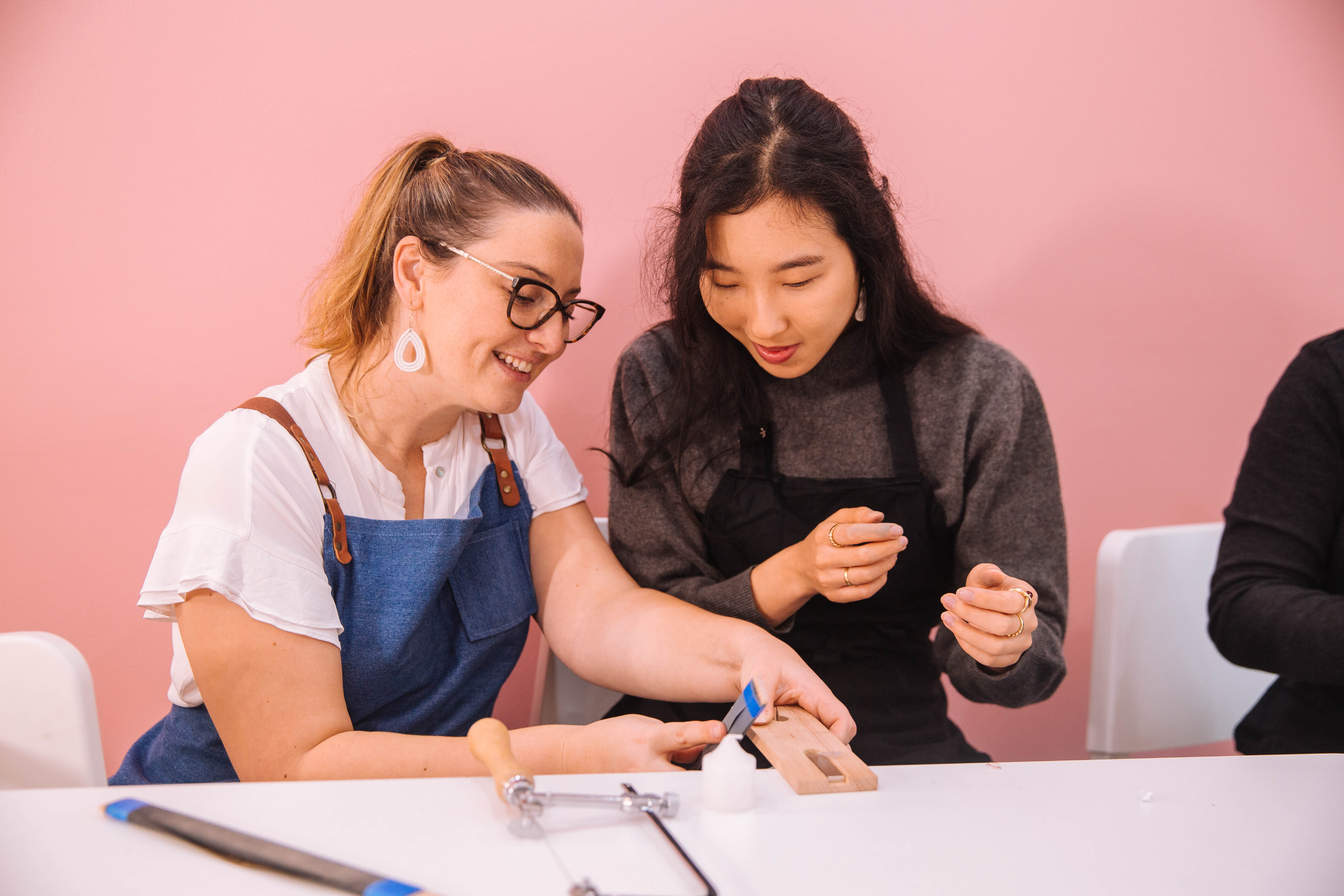 A teacher helps a student at a jewellery making class